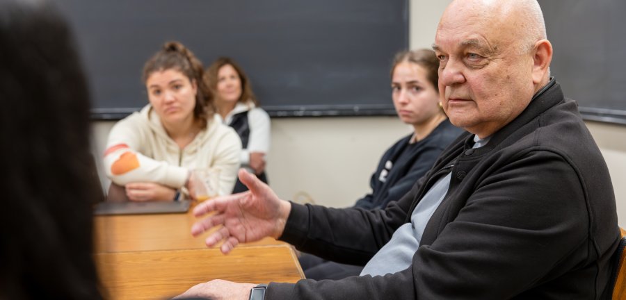 Eugene Nikiforovich in a small classroom setting with students around a table. 