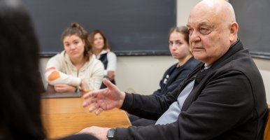 Visiting scholar Eugene Nikiforovich speaks to a class of undergraduate students all seated around a table. 